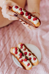 woman holding an eclair with raspberry berries