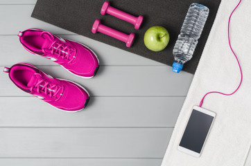 Sport and fitness accessories, healthy and active lifestyle concept on grey wooden floor background with copy space. Products with vibrant, punchy pastel colours. Image taken from above, top view.