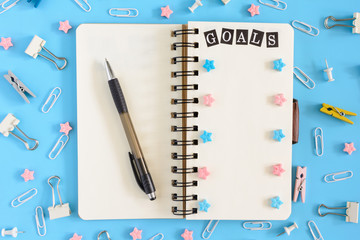 The notepad on the springs lies open, next to the cluttered stationery and pink stars. On the white...