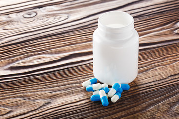 Fototapeta na wymiar Medical blue pills and white bottle on wooden background.