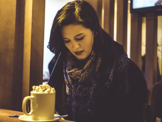 young female student in the cafe drinking coffee sitting at the table
