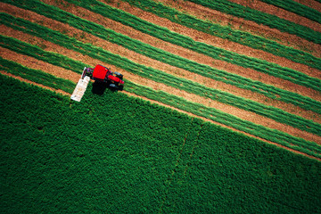 Tractor mowing green field, aerial view