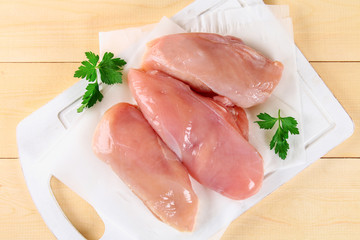 raw chicken fillets on wooden cutting board.