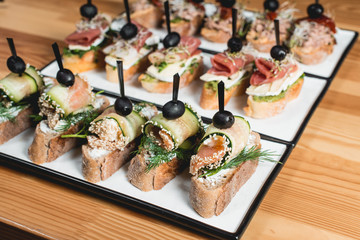 tasty pinchos with tuna, chorizos, salmon, egg, dried tomatoes, avocado, salmon, bacon, Hamon, Brie Cheese, Olives and Pesto Sauce, traditional spanish snack