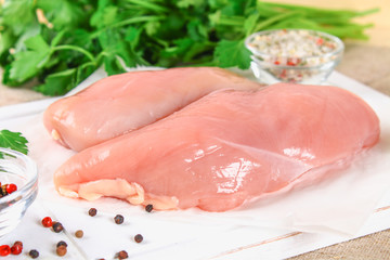 raw chicken fillets on wooden cutting board.