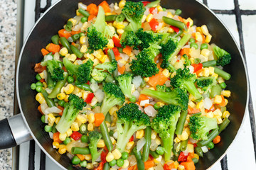 Fresh vegetables in a frying pan. Fresh vegetable products, freshly frozen odietic vegetables carrots are cooked in a frying pan on a gas stove.