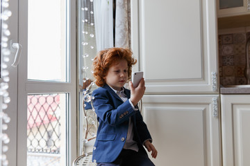 Little redhead boy uses a smartphone
