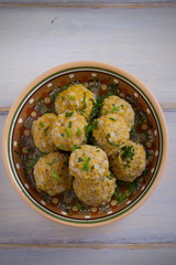 Bowl of meatballs with rice and vegetables on white wooden table