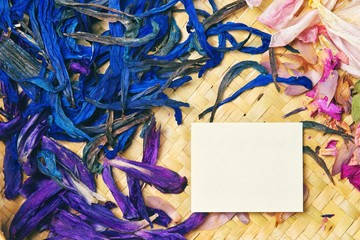 paper card note for wedding or family photo album, frame with violet blue and rose dry flowers isolated on wicker background. flat lay, overhead view