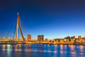 Fototapeta na wymiar Travel Concepts. View of Unique and Beautiful Erasmus Bridge in Rotterdam. City Scyline on the Background. Shot Made During Blue Hour.