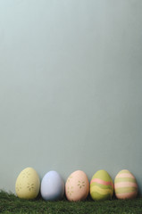Row of Decorated Easter Eggs on Grass with Blue Background
