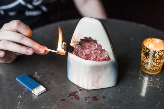 Man smoking shark cocktail over crushed ice