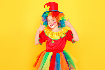Little girl in clown costume and hat showing like sign