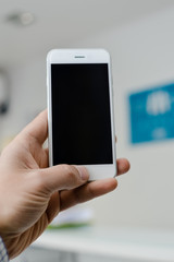 Hand hold mobile phone, person using smartphone. Top view closeup on black screen digital device mock up. Marketing technology design surface background, communication lifestyle