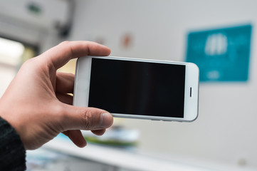 Hand hold mobile phone, person using smartphone. Top view closeup on black screen digital device mock up. Marketing technology design surface background, communication lifestyle