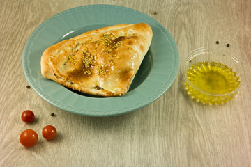 calzone with olive sauce on a wooden background