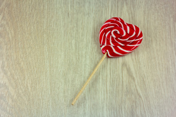 Lollipop in shape of heart on wooden background