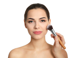 Visage artist applying makeup on woman's face against white background. Professional cosmetic products