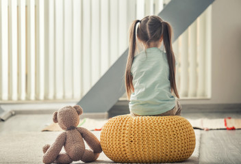 Lonely little girl with teddy bear at home. Autism concept