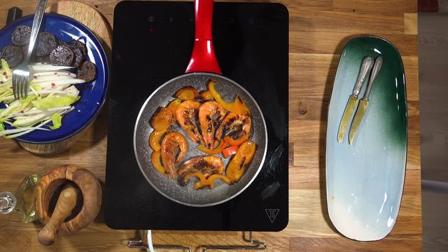 Top view food preparation Shrimp and violet potatoes to the pan on the stove with induction