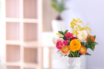 Vase with beautiful ranunculus flowers on blurred background