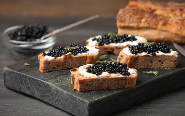 Sandwiches with black caviar and butter on wooden board - obrazy, fototapety, plakaty