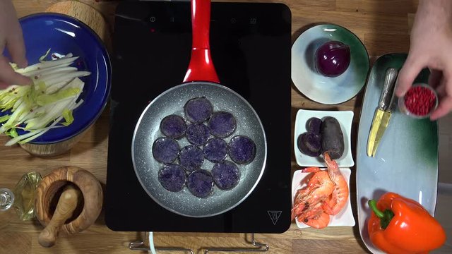 Top view food preparation Shrimp and violet potatoes to the pan on the stove with induction