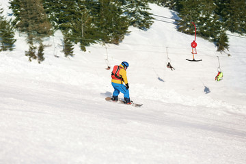 Snowboarder on ski piste at snowy resort. Winter vacation