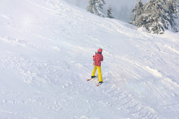 Fototapeta na wymiar Woman on ski piste at snowy resort. Winter vacation