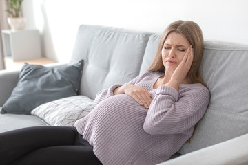 Young pregnant woman suffering from headache at home