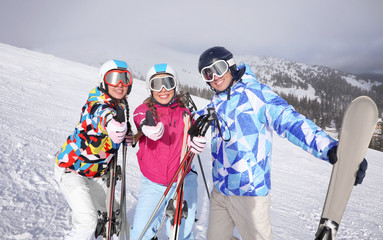 Happy friends on ski piste at snowy resort. Winter vacation