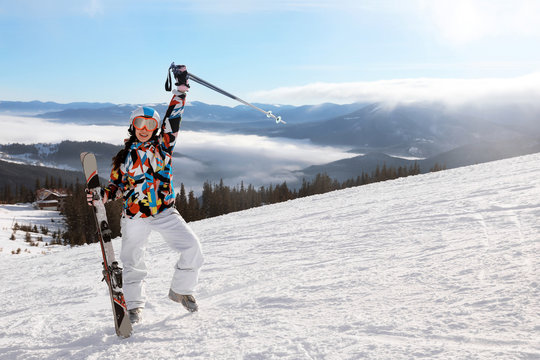 Happy woman on ski piste at snowy resort. Winter vacation