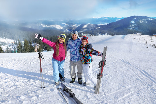Happy friends on ski piste at snowy resort. Winter vacation