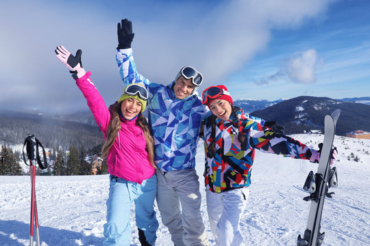 Happy friends on ski piste at snowy resort. Winter vacation