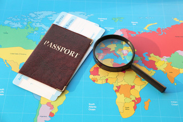 Magnifying glass and passport with arrival cards of immigration bureau on world map