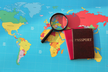Magnifying glass, passports on world map. Immigration concept