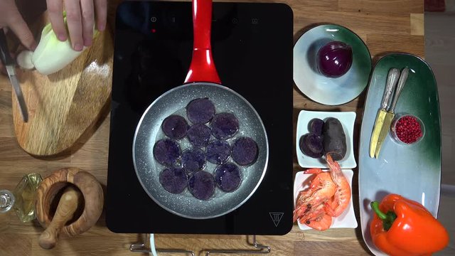 Top view food preparation Shrimp and violet potatoes to the pan on the stove with induction