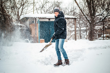 Young man cleaning road with shovel from snow storm
