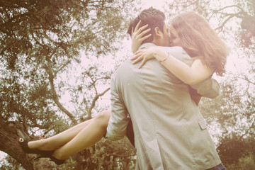 Man carrying a woman and kissing her