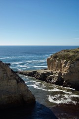 Beautiful coastal view in California (USA): Pacific ocean with limestone rock cliffs with crashing waves, a clear blue summer sky without clouds is the perfect place for tourists to visit