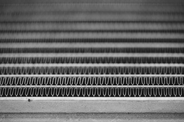 Monochrome background image of automotive radiator close up. Silver background from many duplicate...