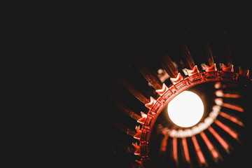 Abstract image of glowing chandelier with red ornament in dark room on black background with copy space.
