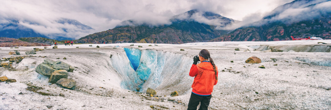 Alaska cruise travel tourist taking photo on activity excursion glacier hike in nature. Banner panorama of woman photographer on summer vacation in USA.