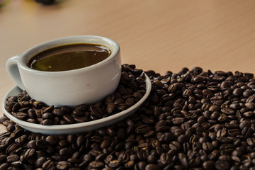 Cup of coffee and beans on the wooden table.