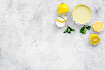 Lemon curd in bowl among lemons on grey background top view copy space