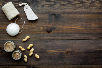 Treatment set with natural peanut scrub to take bath on wooden background top view mock-up