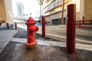 Fototapeta na wymiar Red classic USA fire hydrant with protection on city street