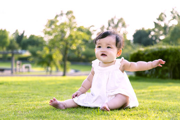 公園の芝生の上に座り一人遊ぶ女の子の赤ちゃん