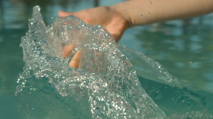 SLOW MOTION, CLOSE UP: Happy young woman plays in tropical holiday resort pool in Fiji. Female on vacation drags her fingertips along the still surface of glassy pool water, creating a cool trail. - Powered by Adobe