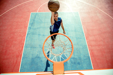 Young man jumping and making a fantastic slam dunk playing streetball, basketball. Urban authentic. © FS-Stock